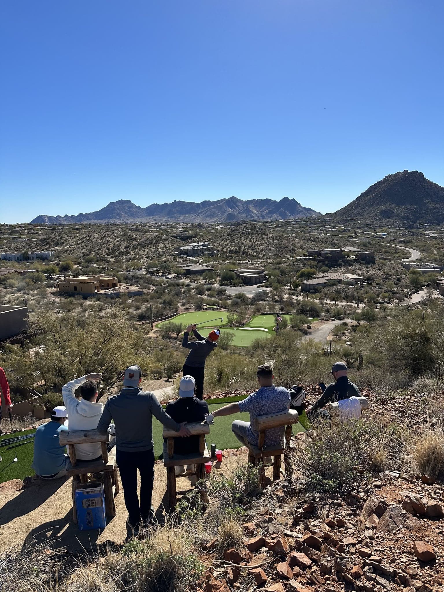 A group of friends relaxing on the private green with panoramic desert views
